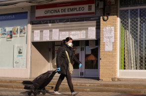 Κορωνοϊός στην Ισπανία: Γυναίκα με προστατευτική μάσκα περνά μπροστά από γραφείο ευρέσεως εργασίας στη Μαδρίτη