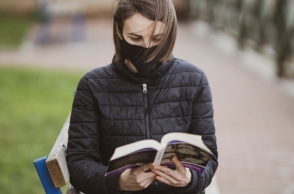 Γυναίκα διαβάζει βιβλίο φορώντας μάσκα