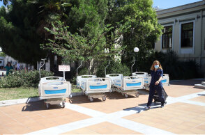 Φορεία στον προαύλιο χώρο νοσοκομείου και γυναικα με ιατρική στολή και μάσκα