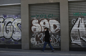 Γυναίκα με μάσκα για τον κορωνοϊό μπροστά από κλειστό κατάστημα στο κέντρο της Αθήνας