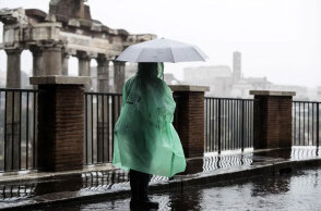 Τουρίστρια με ομπρέλα και αδιάβροχο έξω από τη Ρωμαϊκή Αγορά