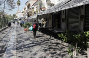 Γυναίκα με τσάντα στην πλάτη περπατά σε πεζόδρομο στο κέντρο της Αθήνας με φόντο τα κλειστά μαγαζιά εν μέσω lockdown