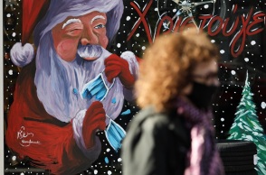 Γυναίκα με μάσκα μπροστά από χριστουγεννιάτικη βιτρίνα