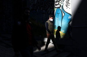 Κάτοικος στην Κωνσταντινούπολη με μάσκα για τον κορωνοϊό περνά μπροστά από κλειστό κατάστημα