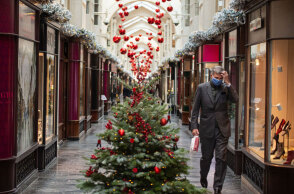 Άνδρας με προστατευτική μάσκα για τον κορωνοϊό περνά δίπλα από χριστουγεννιάτικο δέντρο στο Λονδίνο