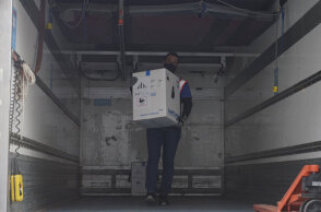 Κορωνοϊός - Κύπρος: Υπάλληλος με προστατευτική μάσκα για τον κορωνοϊό ξεφορτώνει τα πρώτα εμβόλια της Pfizer