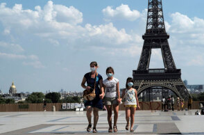 Γαλλία: Τουρίστες με μάσκες για τον κορωνοϊό με φόντο τον Πύργο του Άιφελ στο Παρίσι