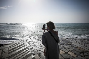 Γυναίκα με μάσκα κάνει βόλτα στη θάλασσα και φωτογραφίζει