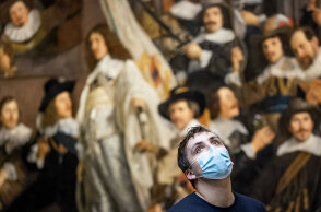 Άμστερνταμ - Rijksmuseum: Νεαρός με μάσκα για τον κορωνοϊό με φόντο τον πίνακα «Νυχτερινή περίπολος» του Ολλανδού ζωγράφου Ρέμπραντ