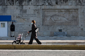 Κορωνοϊός στην Αττική: Μητέρα με το μωρό της, φορώντας μάσκα για Covid-19, περνά μπροστά από το Μνημείο του Αγνώστου Στρατιώτη στο Σύνταγμα