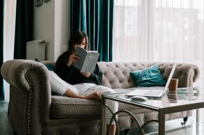 Κοπέλα που κάθεται στον καναπέ και διαβάζει βιβλίο