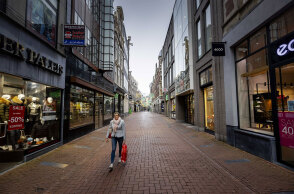 Ολλανδία - Lockdown: Γυναίκα περπατά σε εμπορικό δρόμο στο Άμστερνταμ