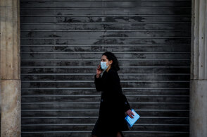 Αττική - Lockdown: Κοπέλα με μάσκα για τον κορωνοϊό μπροστά από κλειστό κατάστημα στην Αθήνα