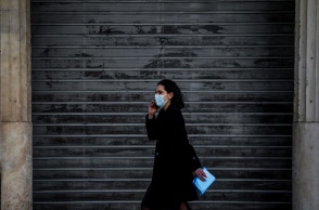 Γυναίκα με μάσκα μπροστά από κλειστό κατάστημα