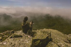 Γυναίκα και σκλυλος στην άκρη του βουνού χαζεύοντας τη θέα
