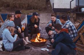 Φίλοι μαζεμένοι γύρω από τη φωτιά στην παραλία