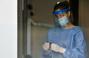 Υγειονομικός του ΕΟΔΥ με μάσκα για τον κορωνοϊό ετοιμάζει rapid test