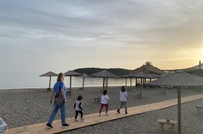 Γυναίκα περπατά σε παραλία με τρία παιδιά