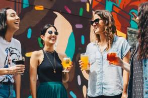 Τέσσερις φίλες που πίνουν ποτό, συζητάνε και γελάνε