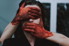 Χέρια με αίματα καλύπτουν πρόσωπο γυναίκας