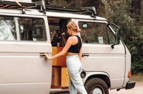 Κοπέλα με τζιν και μαύρη μπλούζα μπροστά από βανάκι στη φύση