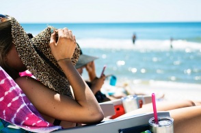 Μια κοπέλα απολαμβάνει τον ήλιο στην παραλία.