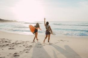 Κορίτσια ετοιμάζονται να βουτήξουν με τη σανίδα του surf στην παραλία.