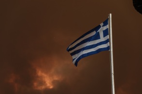 Η ελληνική σημαία με φόντο τον καλυμμένο από καπνό ουρανό στη Βόρεια Εύβοια