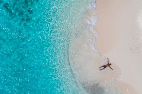 Ένας ανδρας ξαπλώνει στην παραλία και απολαμβάνει τη θάλασσα.