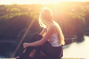 Ένα κορίτσι κάθεται και κοιτά μια λίμνη