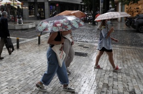 Γυναίκες προστατεύονται από την καταιγίδα κρατώντας ομπρέλα