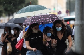 Πολίτες κρατούν ομπρέλα για να προστατευτούν από τον βροχερό καιρό