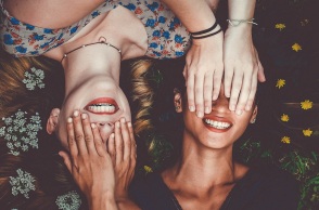 Δύο γυναίκες χαμογελάνε ενώ κλείνουν τα μάτια η μια στην άλλη 