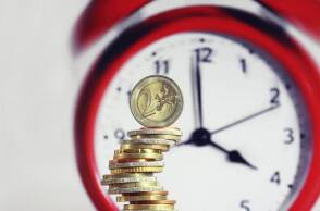 Νομίσματα ευρώ μπροστά από ρολόι