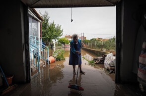 Πλημμύρες στη Βόρεια Εύβοια: Ηλικιωμένη με σκούπα απομακρύνει το νερό της βροχής που έφερε λάσπες και χώματα στο σπίτι της