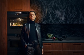 Γυναίκα με μαύρα ρούχα στέκεται μπροστά από φούρνο AEG που λειτουργεί