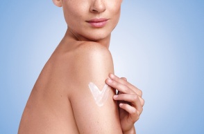 Γυμνή γυναίκα απλώνει ενυδατική κρέμα στο μπράτσο της