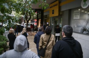 Πολίτες περιμένουν στην ουρά για να μπουν στην τράπεζα
