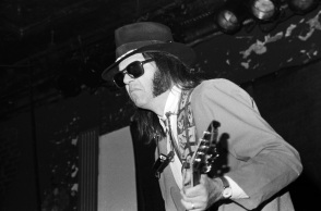 O Neil Young παίζει κιθάρα και φορά μαύρα γυαλιά