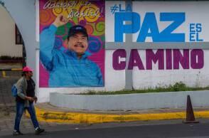 Μια γυναίκα περπατά μπροστά από διαφημιστική αφίσα με την εικόνα του Προέδρου της Νικαράγουας, Ντάνιελ Ορτέγκα