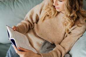 Μια γυναίκα κάθεται στον καναπέ και διαβάζει βιβλίο