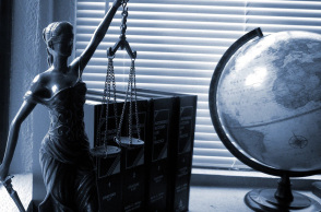 Άγαλμα της θεάς Θέμιδας, θεάς της Δικαιοσύνης, νομοθετικά βιβλία και υδρόγειος σφάιρα πάνω σε γραφείο