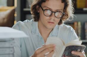 Νεαρός άντρας με γυαλιά, που διαβάζει βιβλίο