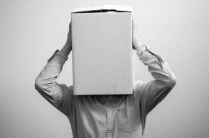 Ασπρόμαυρη φωτογραφία με έναν άντρα που έχει βάλει ένα κουτί στο κεφάλι του