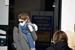 Γυναίκα με μάσκα για κορωνοϊό βγαίνει από κτίριο όπου διενεργείται rapid test από τον ΕΟΔΥ