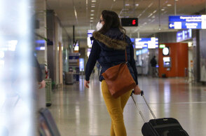 Γυναίκα ταξιδιώτης με μάσκα για τον κορωνοϊό στο αεροδρόμιο «Ελευθέριος Βενιζέλος»