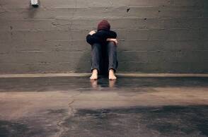 Ένα αγόρι κάθεται μόνο του κρύβοντας το πρόσωπό του