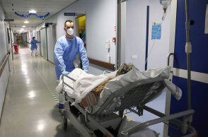 Υγειονομικός οδηγεί ασθενή με κορωνοϊό σε θάλαμο νοσοκομείου στην Κρεμόνα της Ιταλίας