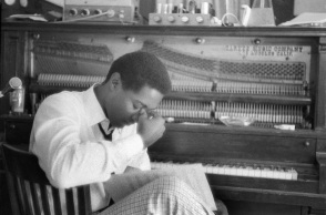 O Sam Cooke πιάνει το μέτωπό του μπροστά από ένα πιάνο