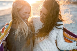 Δύο φίλες που γελούν στην παραλία.